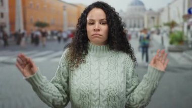 Vatikan meydanında dikilen kadın, klasik mimari ve yoldan geçen turistlerle çevrili İspanyol kültürüne bir bakış sağlayan tarihi zemine karşı kazak giyiyor..