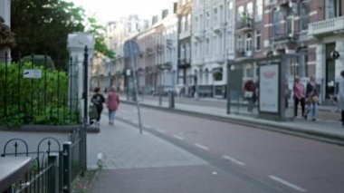 Avrupa şehir kaldırımında yürüyen kadınların olduğu bulanık sokak sahnesi, dağılmış kentsel mimariyi gözler önüne sermek ve yumuşak bokeh ışığı altında rahat açık hava atmosferi.