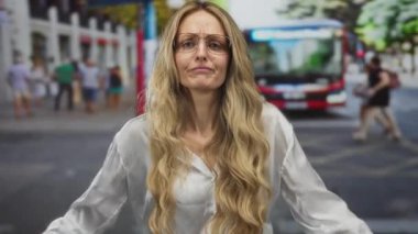 Ağzı açık bir kadın sokakta sesleniyor, genç sarışın şehir sakini gözlüklü banliyö çalışanı otobüsü selamlıyor..