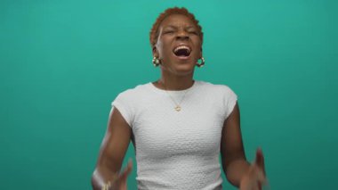 Yeşil stüdyoda çıplak elleri havada ve ağzı açık bağıran beyaz kollu bir kadın. Öfke hüsranı..