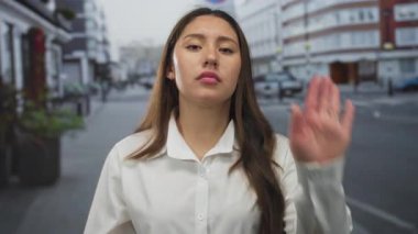 Genç kadın boş şehir sokağında avucunu kaldırıyor cephe ve kaldırım masaları inşa ederek; meydan okuma.