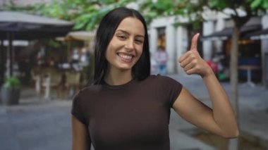 Şehir caddesinde gülümseyen bir kadın, pozitif enerji ve İspanyol kültürünü tasvir eden açık havada olumlu bir işaret veriyor..