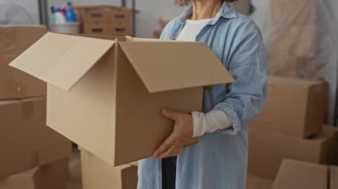 Kartonla çevrili yeni bir evde kutuları açan kadın, mutluluk ve heyecanı ifade ediyor, İspanyol etnik kökenini ve esmer saçı yerli bir ortamda vurguluyor..