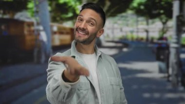 İspanyol adam gülümsüyor ve yeşil parkta arka planda ağaçlarla elini uzatıyor. Açık havada dostça davranışlar sergiliyor. Gündüz vakti genç doğal eğlence çekici..