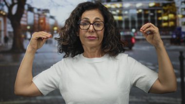 Orta yaşlı İspanyol kadın, meşgul bir şehir caddesinde elleri ile konuşma jesti gösterdi; iletişim ifadesi nişan konuşması.