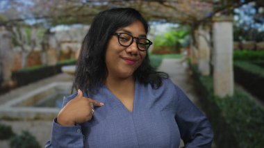 Kadın gülümser ve kendini bir binaya mermer sütunlarla çerçevelenmiş taş bir çeşmenin yanında gösterir..