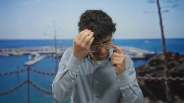 Adam çerçeveye dokunarak bardakları ayarlar ve paslı zincirlerin yanında güneş ışığı altında şaşı kalır ve kalabalık bir iskelede bir caddede rıhtıma yanaşmış bir tekne; sessiz bir odak.