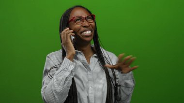 Cep telefonuyla konuşan bir kadın, izole edilmiş yeşil arka planda neşeli bir iletişim sergiliyor..