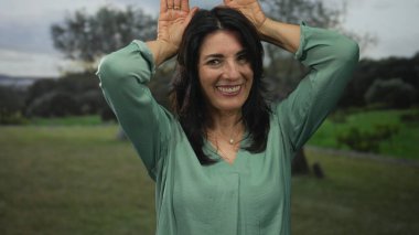 Yeşil bluzlu kadın gülüyor ve ormanda el ele tutuşuyor gün ışığında temizleniyor; neşe, neşe, eğlence, mutluluk..