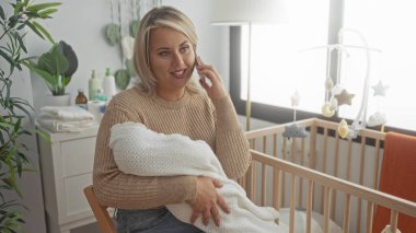 Kadın yeni doğan bebeği battaniyeye sarar ve apartman odasındaki ahşap beşiğin yanında akıllı telefondan kulağa tutar; annelik şefkati.