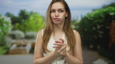 Taş bankın yanındaki ormanda yapraklı tepe örtüsü altında eklemlerini ısıran bir kadın..