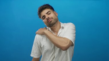 Stüdyoda el ele tutuşan beyaz keten gömlek giyen ve sakalını kesen İspanyol genç bir adam..