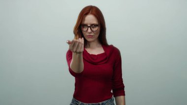 Öfkeyle işaret eden ve işaret veren bir kadın kırmızı saçlı, gözlüklü ve beyaz arka planda izole edilmiş kırmızı bluzu olan buraya gelir..
