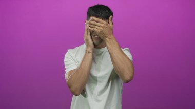 Stüdyoda beyaz t-shirt 'lü bir erkek yüzünü mora boyayarak kapatır. Utanç..