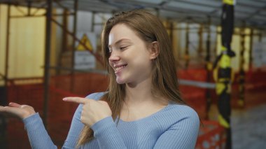 Mavi kazaklı genç beyaz kadın inşaat alanının önünde el işareti yapıyor, onaylandı..