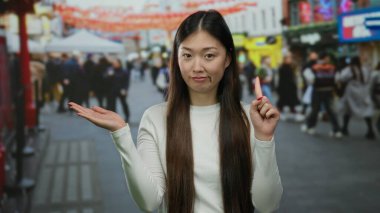 Hayır diyen bir kadın, arka planda canlı şehir hayatı ve kültürel unsurlarla çevrili, Çin 'deki işlek şehir caddesinde açık avuçla işaret ediyor..