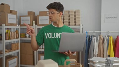 Gönüllü adam dizüstü bilgisayarı işaret ediyor ve bağış kutusunda bağış kutularını inceliyor; şefkat.