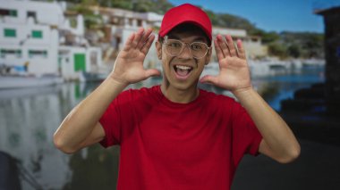 Kırmızı şapkalı ve gömlekli adam güneşli caddedeki limanda limandaki teknenin yanında elleri olan gözleri geniş bir gülümsemeyle kaplıyor..