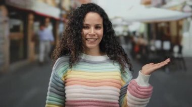 Renkli kazaklı genç İspanyol kadın gün içinde bir restoran ve kahve dükkanının yakınındaki bir sokak terasında bir şey sunar..