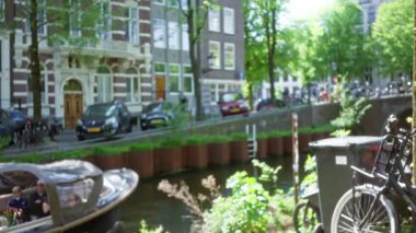 Kanal yakınındaki bir ağacın yanında tekneli bisikletler ve arka planda bulanık şehir manzarası, güneşli bir günde mükemmel bir Alman kentsel yaşamını odaksız bir sükunetle yakalıyor..