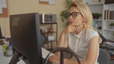 Kadın, masa rafları, bitki ve mikrodalga fırının olduğu bir binanın içinde bilgisayar ekranında çalışıyor; yansıma.