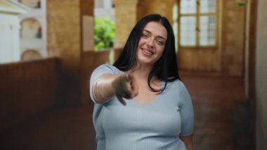 Yaşlı bir üniversitenin kapalı koridorunu gösteren, kendine güvenen, tarihi mimariyle çevrili, açık mavi bluzlu genç bir kadın..