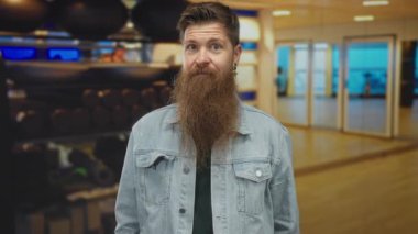 Spor salonunda ağırlık kaldırma ve egzersiz toplarıyla dolu bir spor salonunda tırnak işareti yapan genç bir adam..