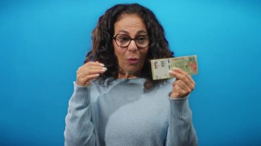 Arjantin pesolarını soyutlanmış mavi arka planda tutan kadın para birimi değeri üzerinde heyecan gösteriyor.