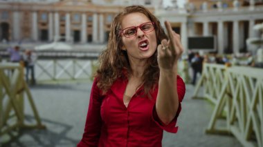 Kırmızı gömlekli kadın Aziz Peter Meydanı 'ndaki Vatikan' da el hareketi yapıyor. Bulanık insanlar ve arka planda mimari anlayışı açık havada tutumunu gösteriyor..