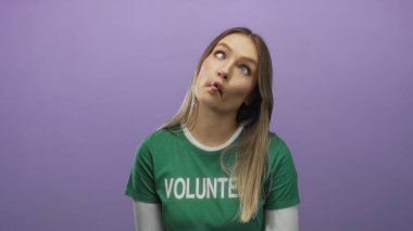 Kadın gönüllü, mor arka plana karşı neşeli bir ifade takınıyor yeşil gömlekli, izole edilmiş bir ortam..