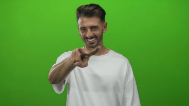 Erkek, canlı yeşil bir stüdyo duvarına karşı başparmağıyla kolunu kaldırır. Pozitiflik..