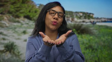 Kadın dudakları parkta mavi gökyüzünün altında öpüşüyor ağaçların arasında ve gözleri kapalı çimenler gözlük takıyor; şefkat sıcaklığı.