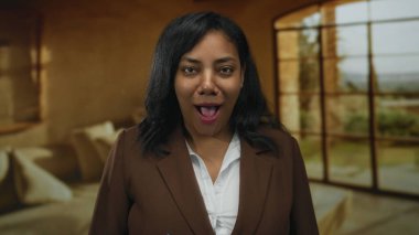 Oturma odasında konuşan Afro-Amerikalı kadın kameraya bakıyor..