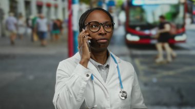 Şehir merkezinin dışında, steteskop ve kızgın ifadeyle konuşan bir doktor..