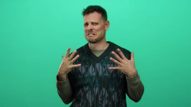 Genç adam, izole edilmiş yeşil arka plan duvarından tiksinerek tepki veriyor.
