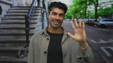 Ringbone ceketli gülümseyen İspanyol genç adam şehir sokaklarında çıplak yüzüyle dalgalanır..