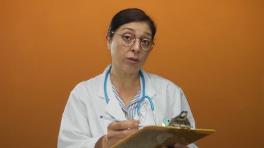 Stüdyoda boynunda steteskopla panoya notlar yazan İspanyol doktor..