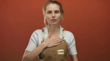 Göğüs göğüse söz veren, önlük giyen, canlı kırmızı arka plana karşı duran, samimiyet ve bağlılığı somutlaştıran, dürüstlük ve adanmışlık teması için mükemmel bir kadın..