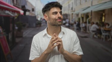 Sakallı, beyaz gömlekli genç İspanyol adam hareketli şehir caddesinde el ele tutuşuyor..