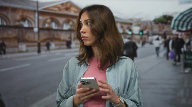 Yoğun şehir caddesinde akıllı telefon kullanan bir kadın, şehir ortamında mobil teknolojiyle meşgul olan genç İspanyol kadınları yakalıyor..