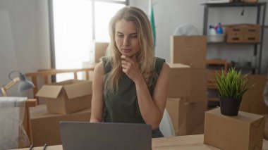 Yeni apartman dairesinde çalışan bir kadın oturma odasında dizüstü bilgisayar kullanarak yeşil ve ışık dekoru elementleriyle hareket ettiğini gösteriyor..