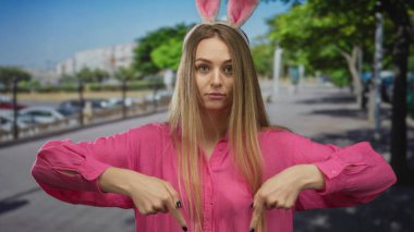 Şehir caddesinde tavşan kulağı takan bir kadın, şehir merkezindeki açık hava ortamında, hareketli ve kaprisli titreşimleri vurguluyor..