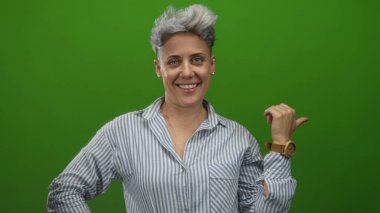 Stüdyoda sırıtırken bileğindeki ahşap saati gösteren kısa saçlı beyaz kadın..