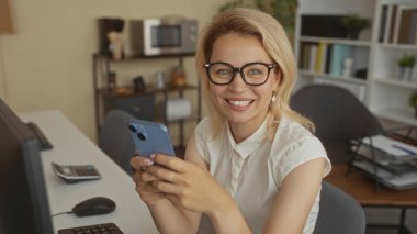 Binada sırıtırken akıllı telefonu tutan ve ekranı tıklatan kadın; dijital bağlantı mutluluğu.