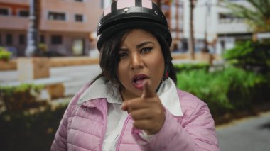 Şehir parkı ortamında kask takan kadın özgüvenini odaklanmış bir ifadeyle ifade ediyor..