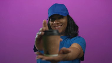 Teslimatçı kadın, stüdyoda uzanmış elleri mor duvarlı kahve bardağını tutuyor; servis sıcaklığı konukseverliği..