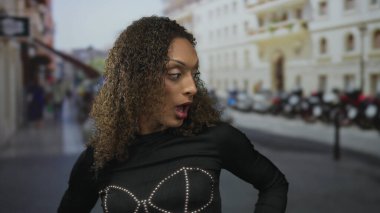 Açık ağızlı, kıvırcık saçlı, siyah bluzlu, park halindeki motosikletli bir kadın. Sürpriz..