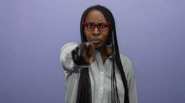 Gözlüklü, örgülü, mor duvara kızgın bir şekilde bakan kadın güçlü bir duygu ifadesi sergiliyor. Kendine güvenen bir tavır sergiliyor..