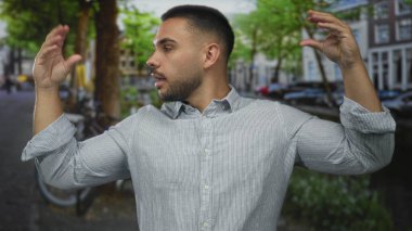 Erkek jestleri şehrin cadde köşesinde iki elini de kaldırarak konuşur; sosyal etkileşim.