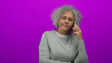 Telefondaki kadın canlı pembe bir arka planda konuşuyor. Odaklanma ve konsantrasyon yayıyor. Düşünceli bir iletişim anında görüntüleniyor..